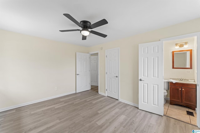 unfurnished bedroom featuring baseboards, light wood finished floors, a sink, and connected bathroom