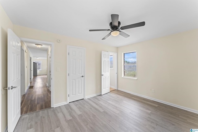 unfurnished bedroom with light wood-type flooring, baseboards, and a ceiling fan