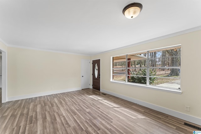 interior space featuring baseboards, crown molding, visible vents, and wood finished floors