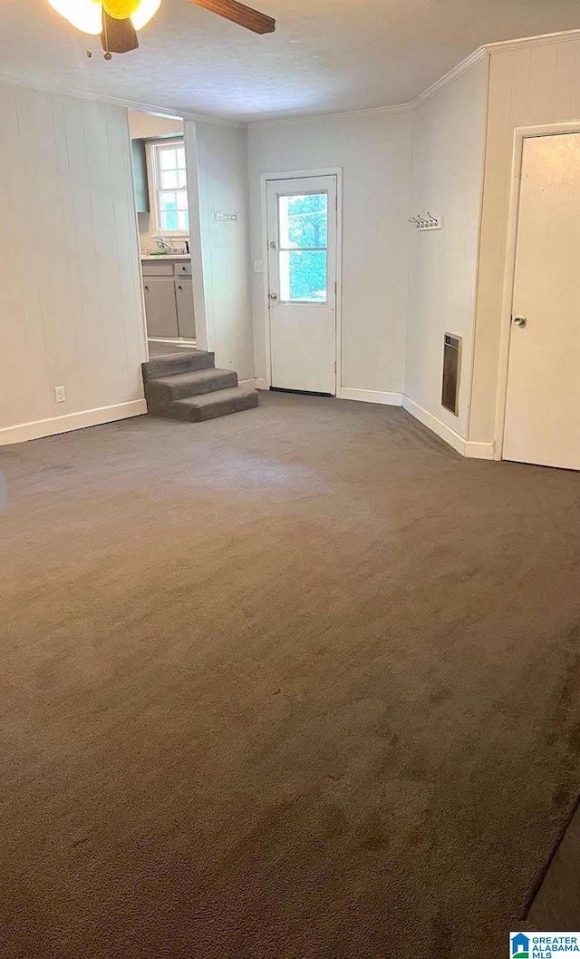 unfurnished living room with crown molding, carpet flooring, a ceiling fan, and a wealth of natural light