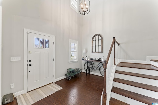 entryway with baseboards, a towering ceiling, stairway, wood finished floors, and an inviting chandelier