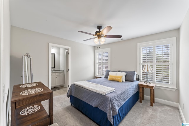 bedroom featuring ensuite bathroom, light carpet, a ceiling fan, visible vents, and baseboards