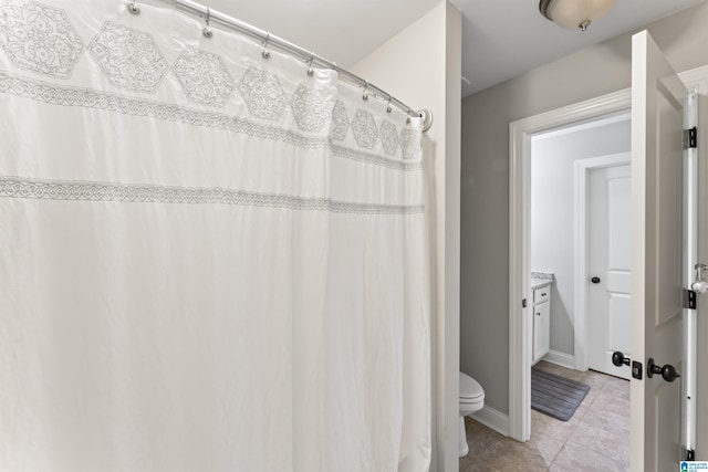 full bath with tile patterned flooring, toilet, and baseboards