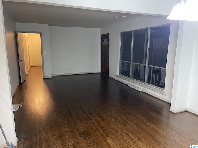 empty room featuring dark wood-style floors and baseboards