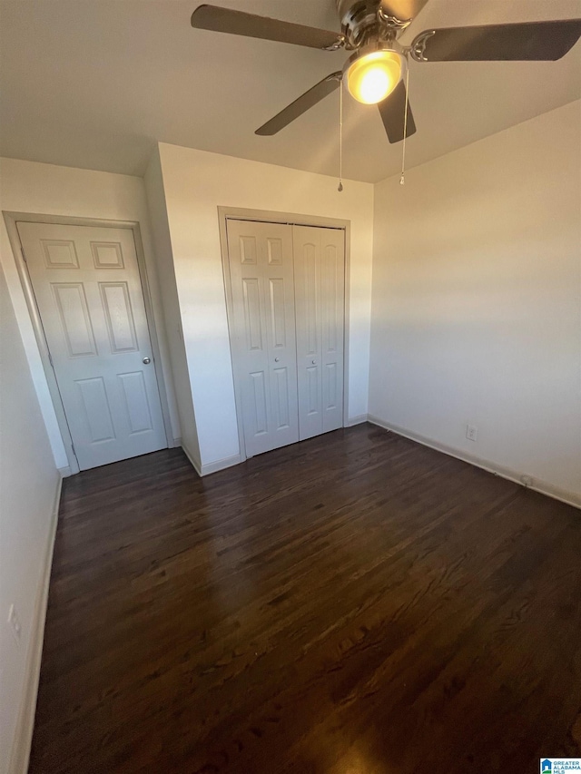 unfurnished bedroom featuring ceiling fan, dark wood-style flooring, a closet, and baseboards