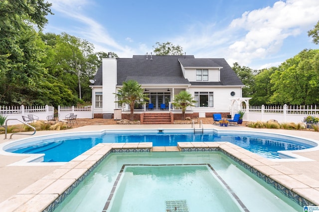 view of pool featuring a patio, fence, and a pool with connected hot tub