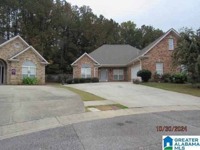 view of front of home featuring an attached garage, concrete driveway, and brick siding