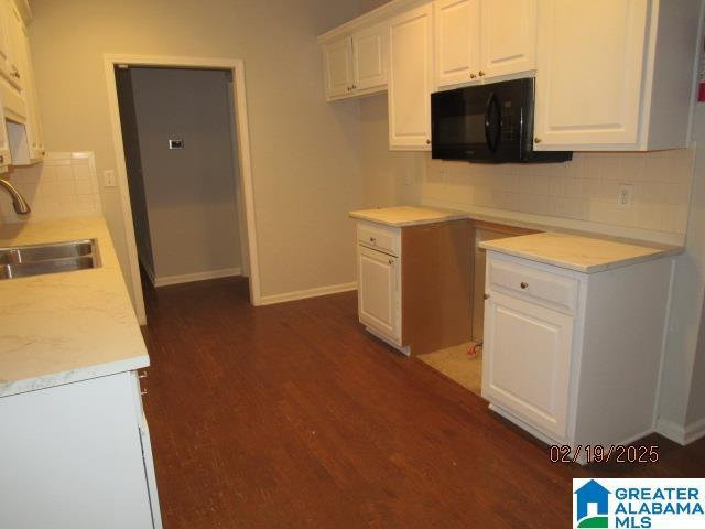 kitchen with white cabinetry, black microwave, dark wood-type flooring, and a sink