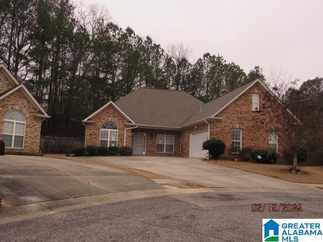 view of front of house featuring concrete driveway, brick siding, fence, and an attached garage