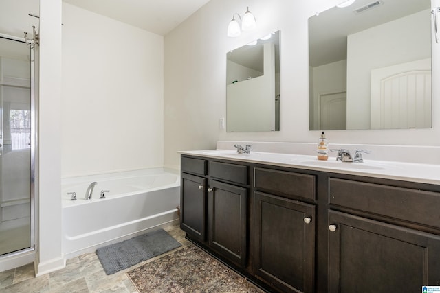 full bathroom with double vanity, a garden tub, visible vents, and a sink