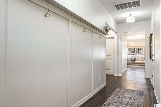 corridor with dark wood-type flooring, visible vents, and baseboards