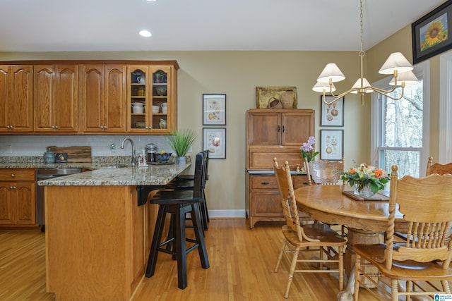 kitchen with brown cabinetry, dishwasher, and a kitchen bar