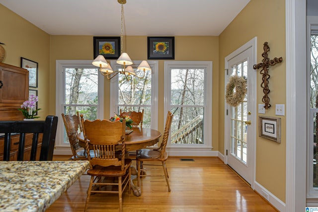 dining area with light wood-style floors, baseboards, visible vents, and a notable chandelier