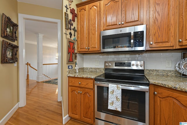 kitchen with appliances with stainless steel finishes, backsplash, light stone counters, and light wood-style floors