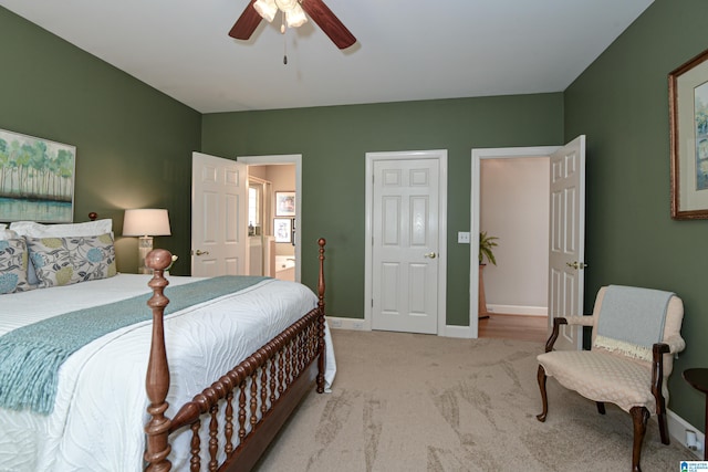 bedroom with light carpet, connected bathroom, baseboards, and ceiling fan