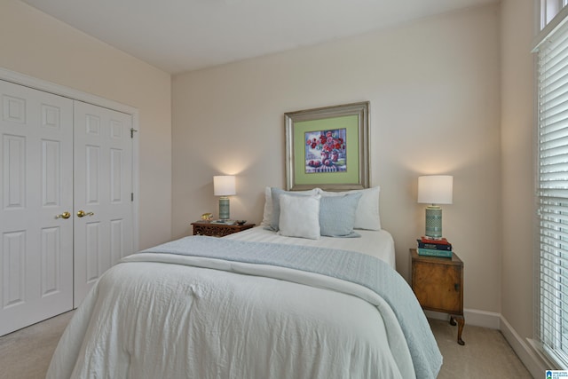 bedroom with light carpet, a closet, and baseboards