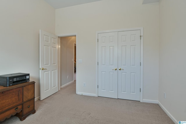 bedroom with a closet, light carpet, and baseboards