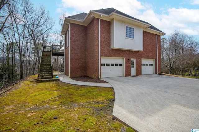 view of property exterior featuring driveway, an attached garage, stairs, and brick siding