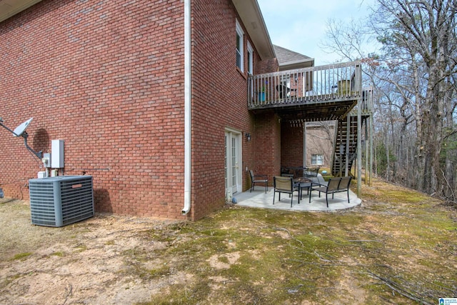 view of property exterior featuring central AC unit, stairway, a deck, a patio area, and brick siding