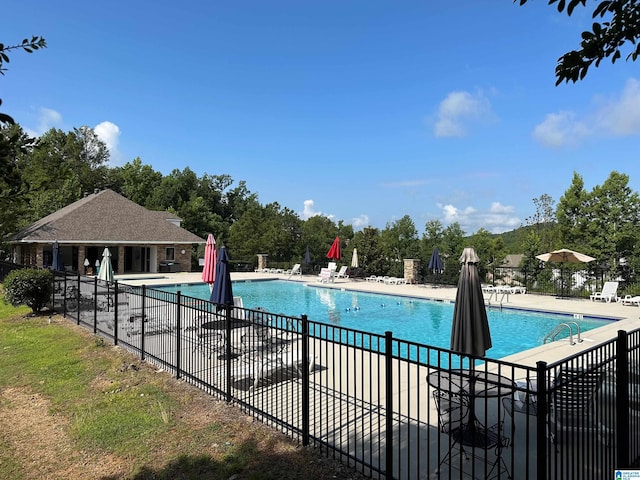 community pool with a patio area and fence