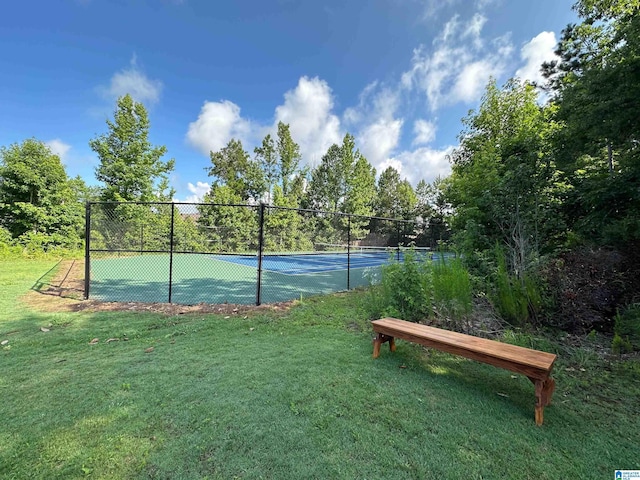 view of tennis court featuring a yard and fence