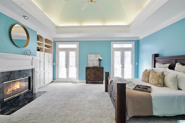 bedroom with access to outside, french doors, a raised ceiling, and multiple windows