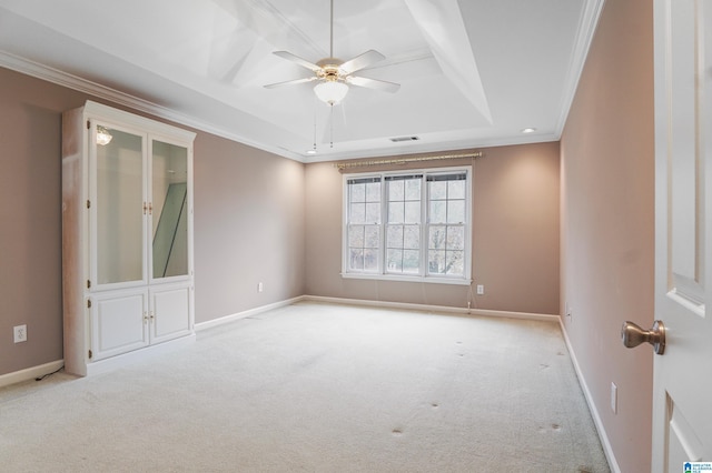 spare room with light carpet, baseboards, visible vents, a tray ceiling, and crown molding