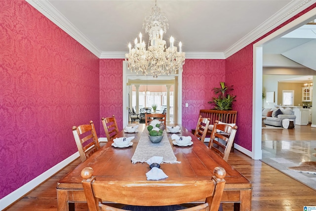 dining area with wallpapered walls, baseboards, ornamental molding, wood finished floors, and a chandelier