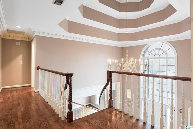 corridor featuring visible vents, ornamental molding, wood finished floors, and an upstairs landing