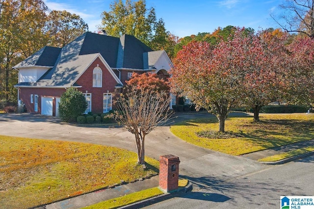 traditional-style house featuring driveway, a garage, a front lawn, and brick siding