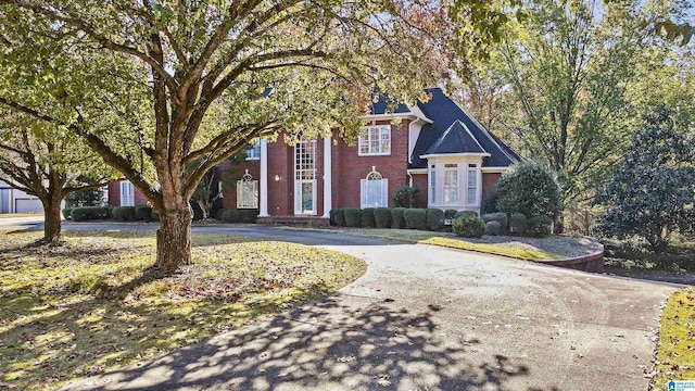 neoclassical home with driveway and brick siding