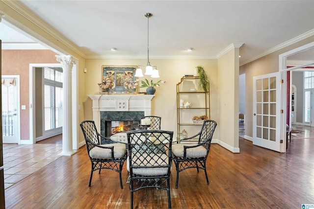 dining room featuring crown molding, a fireplace, baseboards, and wood finished floors