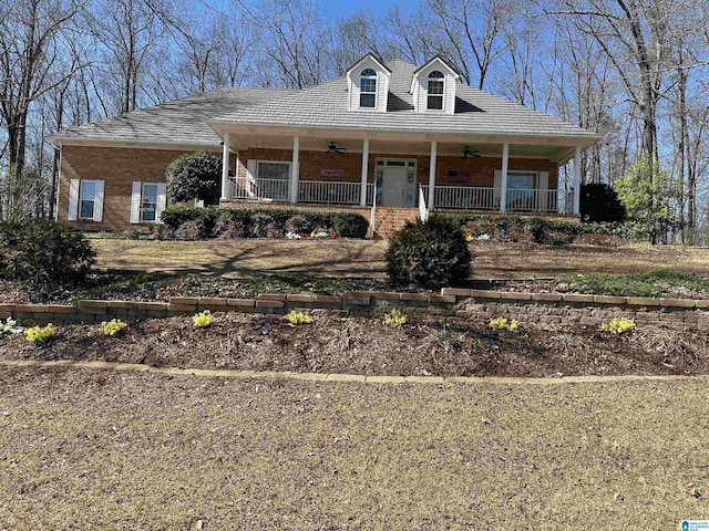 country-style home with a ceiling fan, covered porch, and brick siding