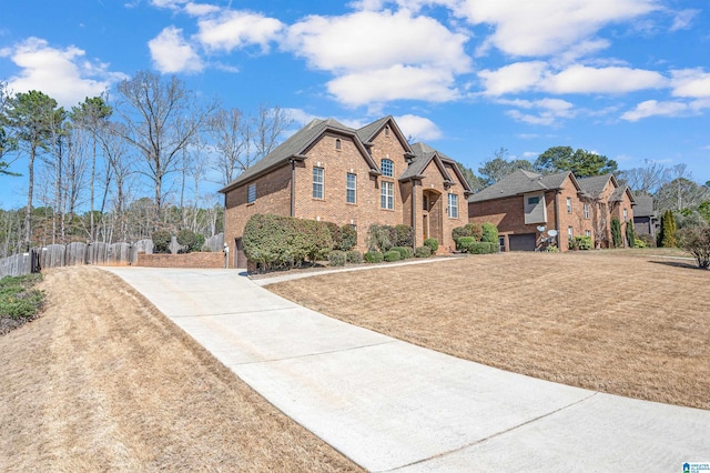 view of front of house featuring driveway, a front yard, fence, and brick siding