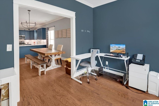 office featuring an inviting chandelier, ornamental molding, a sink, wood finished floors, and baseboards