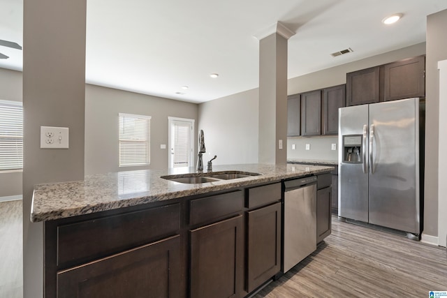 kitchen featuring light stone counters, light wood finished floors, stainless steel appliances, visible vents, and dark brown cabinets