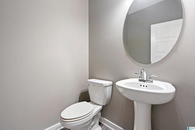 bathroom featuring toilet, baseboards, and a sink