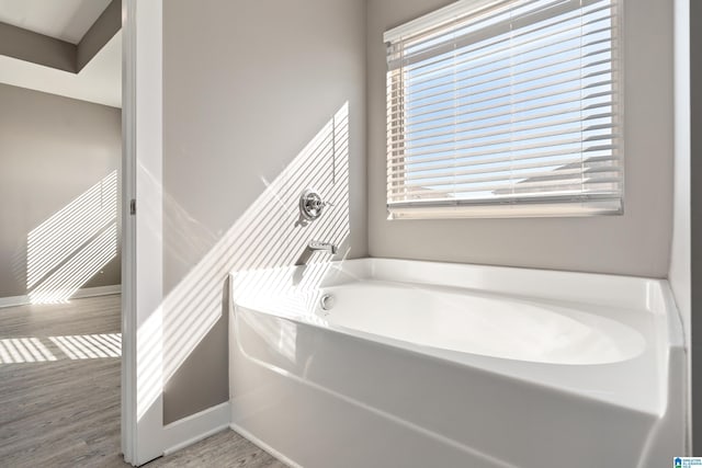 full bath featuring a bath, baseboards, and wood finished floors