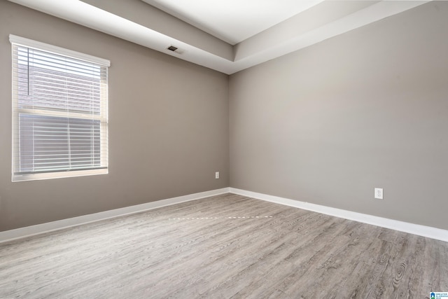 unfurnished room featuring visible vents, baseboards, and wood finished floors