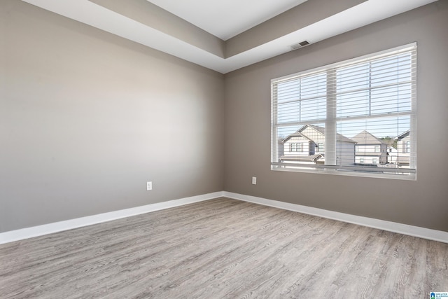 spare room with wood finished floors, visible vents, and baseboards