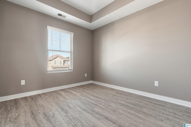 empty room featuring baseboards, visible vents, and wood finished floors