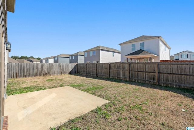 view of yard with a patio, a fenced backyard, and a residential view