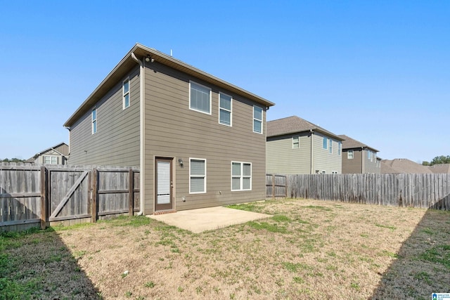 rear view of house featuring a lawn, a patio area, a fenced backyard, and a gate