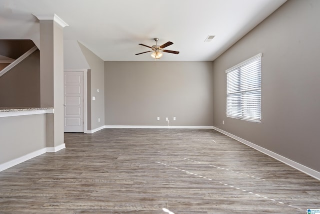 spare room with ceiling fan, wood finished floors, visible vents, and baseboards