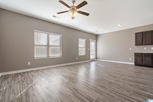 unfurnished living room featuring ceiling fan, wood finished floors, visible vents, and baseboards