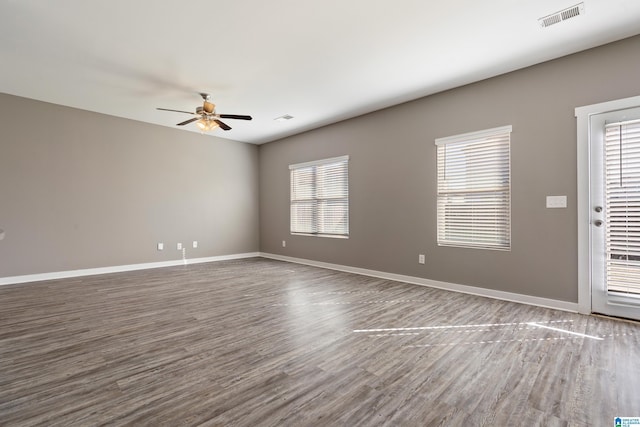 spare room with visible vents, ceiling fan, baseboards, and wood finished floors