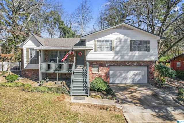 split level home with a porch, a garage, brick siding, stairs, and concrete driveway