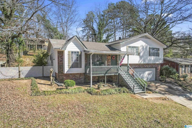 tri-level home with an attached garage, a porch, concrete driveway, and brick siding