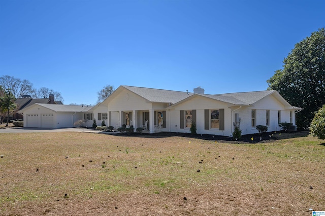 view of front of home featuring an attached garage, driveway, a chimney, and a front yard