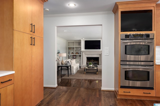 kitchen with dark wood-style flooring, ornamental molding, stainless steel double oven, and built in features